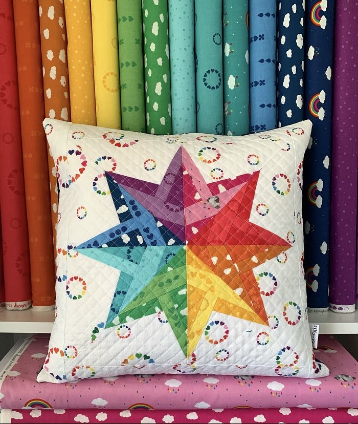 evening star paper pieced pattern sewn in rainbow fabrics and turned into a cushion