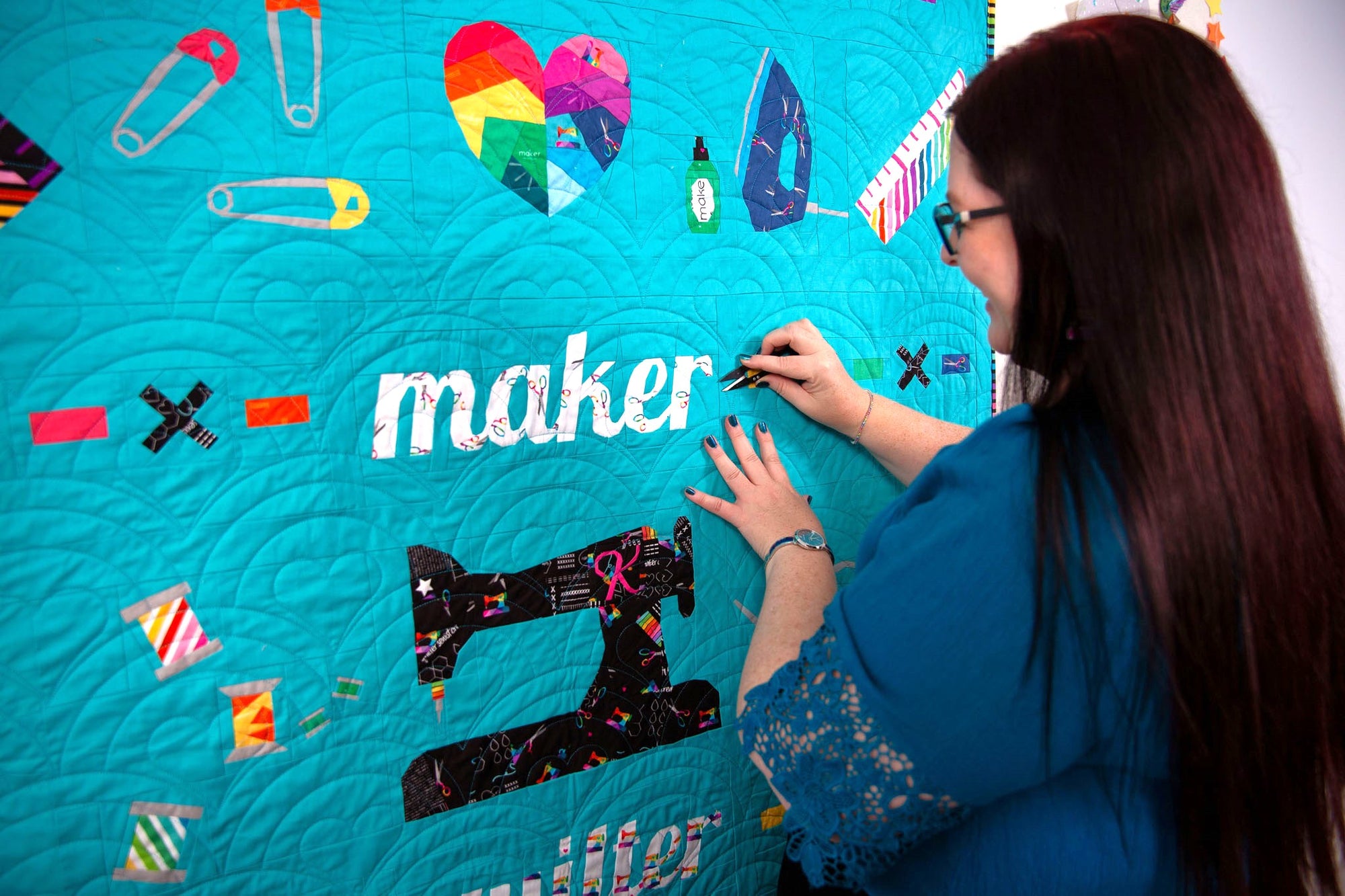 A turquoise FPP quilt with sewing themed illustrations.