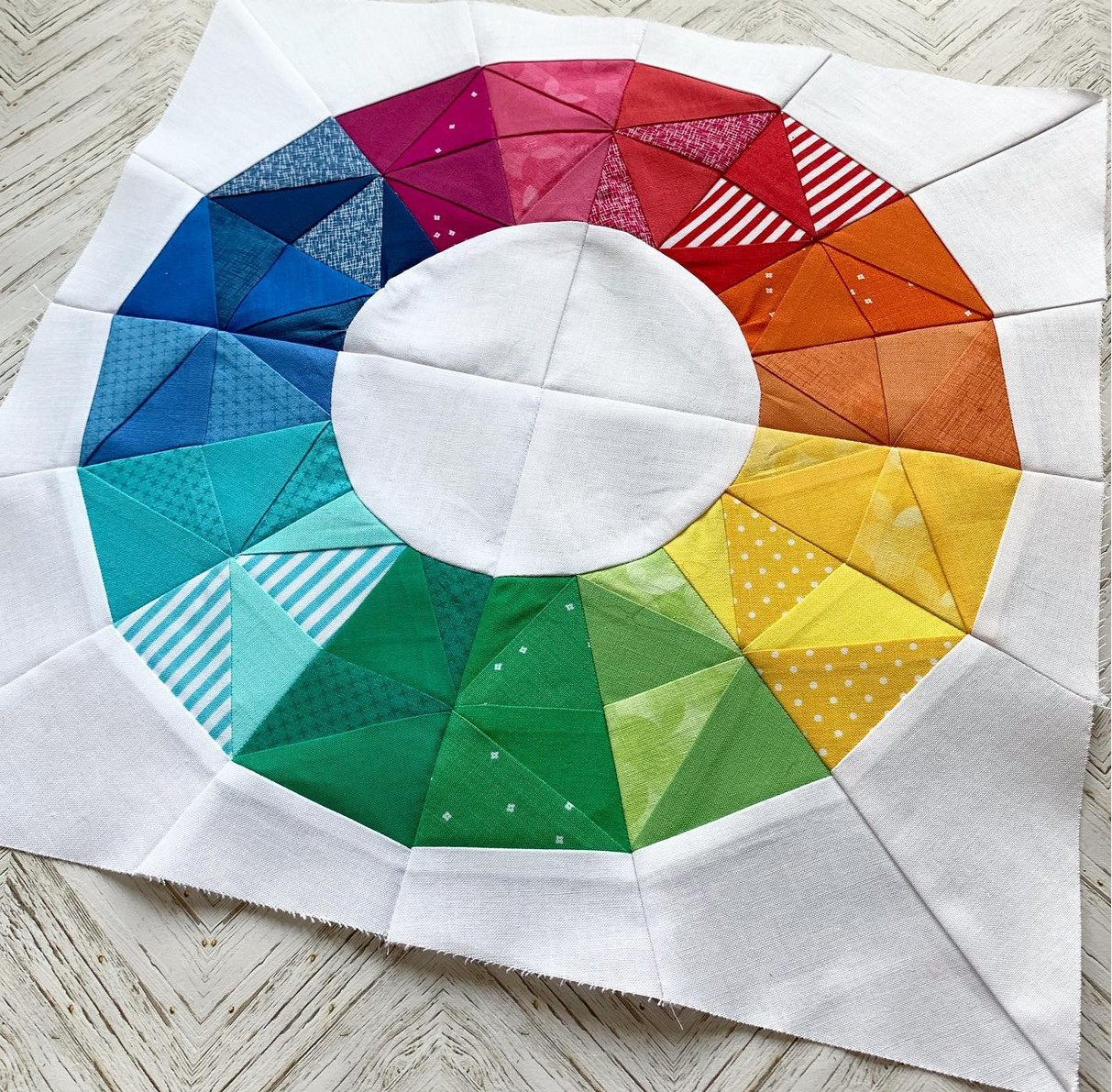geometric fractured rainbow paper pieced pattern similar to a colour wheel sewn in rainbow fabrics
