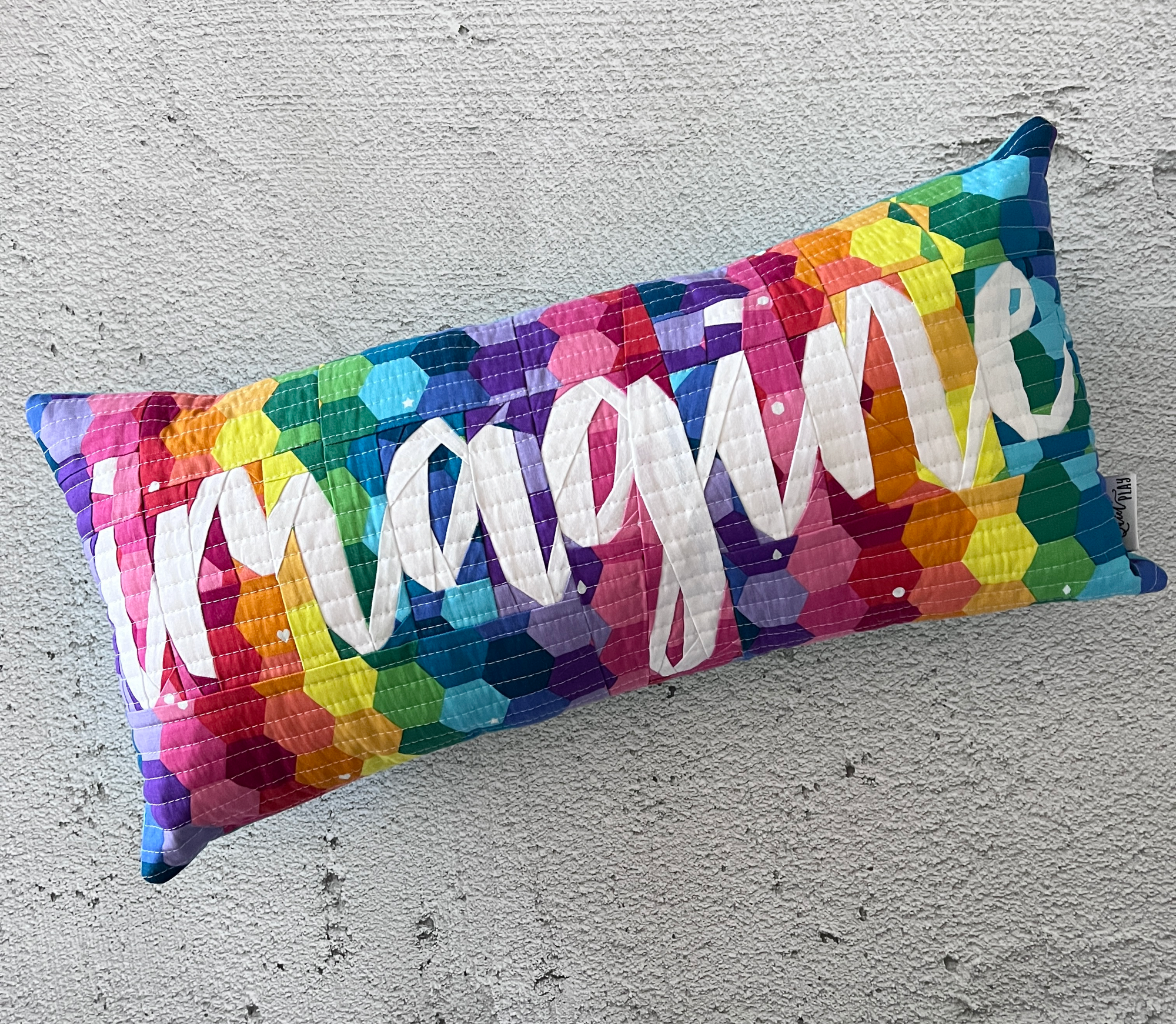 imagine in script paper pieced pattern sewn in bright fabrics sewn into a pillow